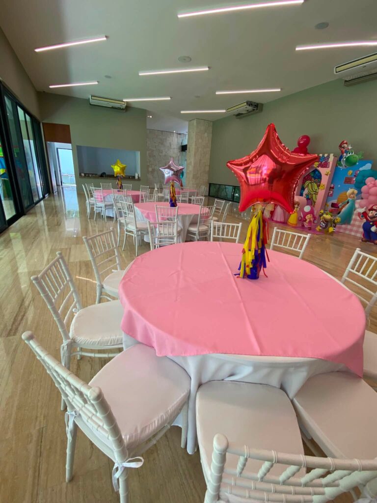 Mesa redonda con mantel rosa y sillas Tiffany blancas de Divertiplaya en Playa del Carmen