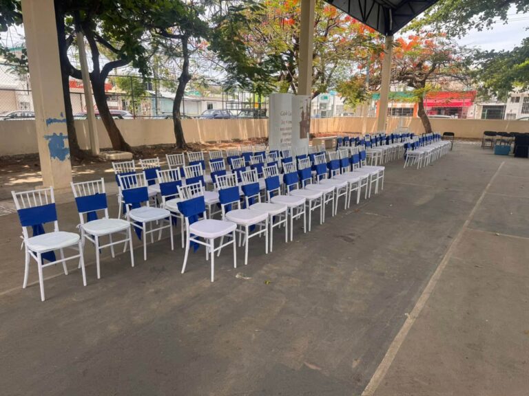 Sillas blancas con moños azules montadas para un evento de Divertiplaya en Playa del Carmen