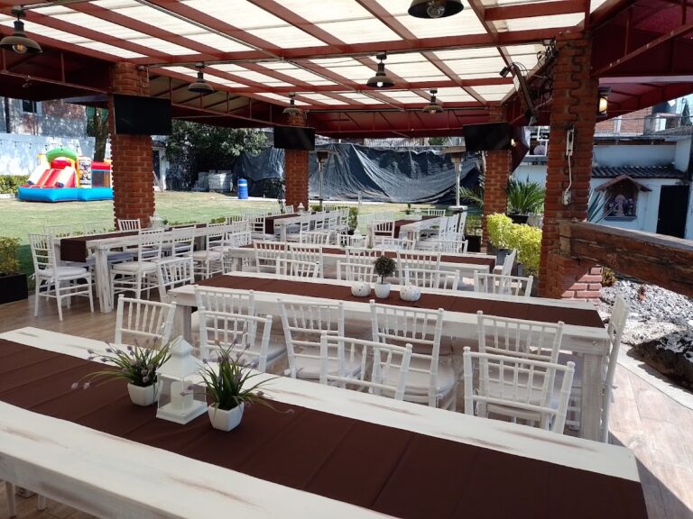 Mesas largas de madera blanca y sillas Tiffany bajo pérgola de Alquiladora Petit en CDMX