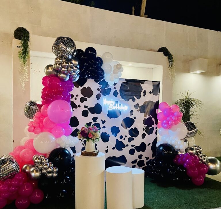 Arco de globos rosa, negro y plata con fondo de manchas de vaca
